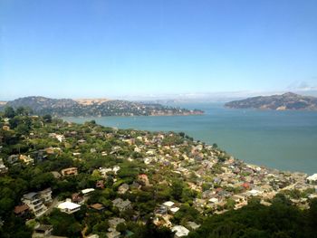 High angle view of cityscape and sea against clear sky