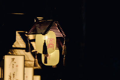 Low angle view of illuminated lighting equipment against black background