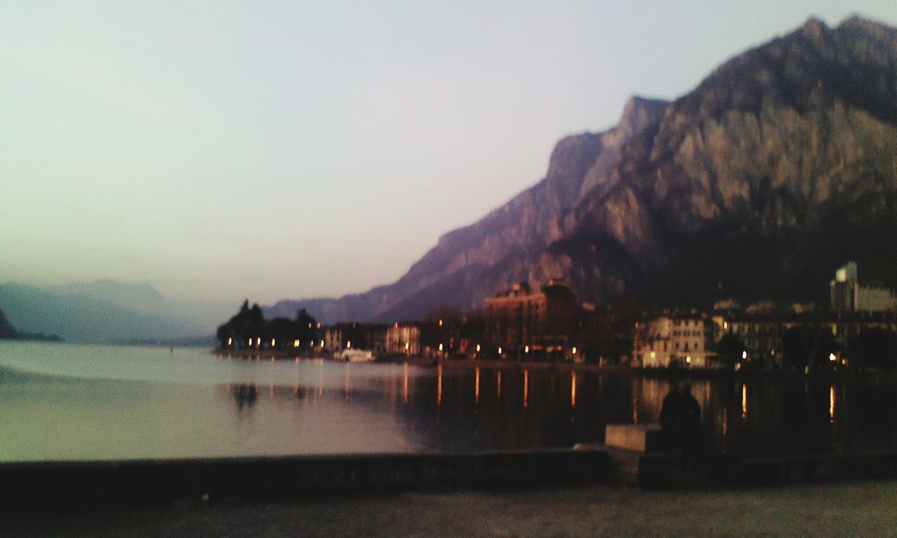 water, mountain, tranquil scene, reflection, waterfront, tranquility, scenics, sea, lake, beauty in nature, clear sky, mountain range, nature, sky, copy space, dusk, idyllic, rock - object, calm, silhouette