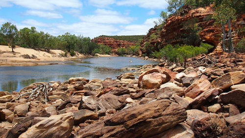 Scenic view of rock formation by trees against sky