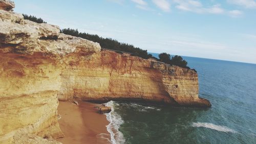 Rock formations by sea against sky