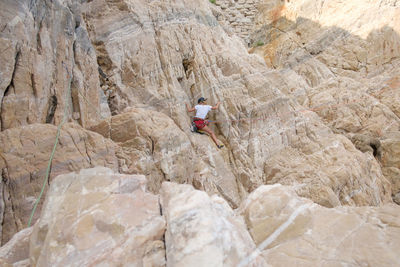 Rear view of woman climbing on rock