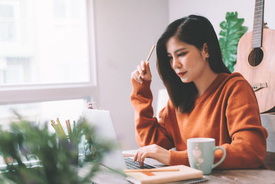 Young woman using phone while sitting on table