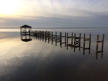 Incomplete pier on calm river against sky