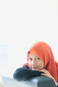 Portrait of young woman sitting against wall