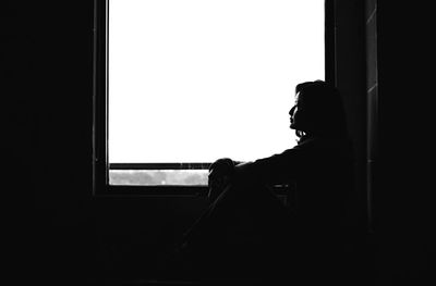 Side view of silhouette woman standing against window