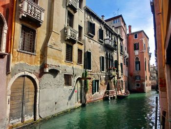 Canal amidst buildings on sunny day