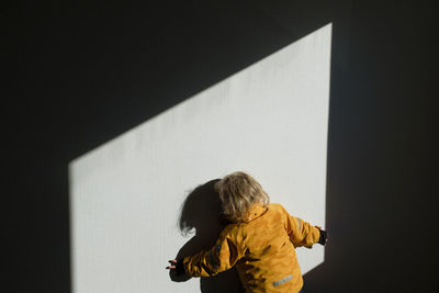 Rear view of woman standing against wall