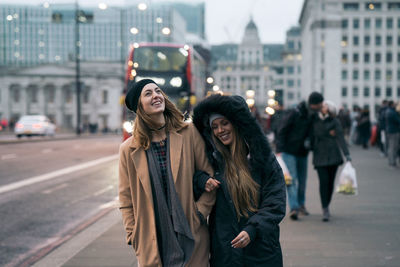 Smiling friends walking on road in city