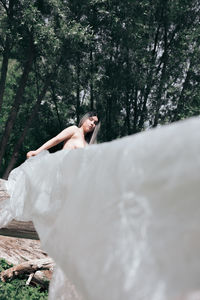 Naked woman holding polythene standing in forest