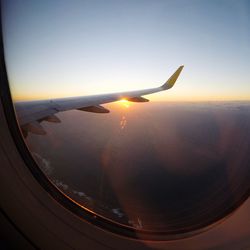 Airplane flying over sea against sky during sunset