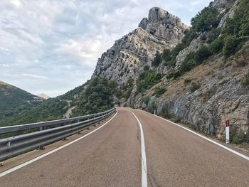 Road by mountains against sky