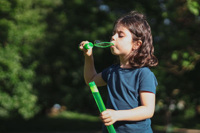 Portrait of a beautiful caucasian girl blows soap bubbles standing in the park