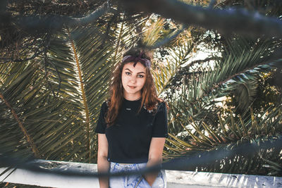 Portrait of young woman standing against trees