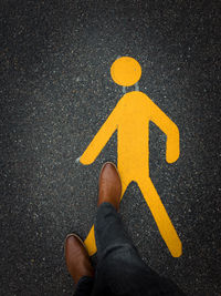 Low section of person with yellow arrow sign on road