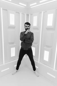 Full length portrait of young man standing against wall