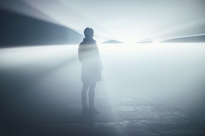 Rear view of silhouette man walking in fog