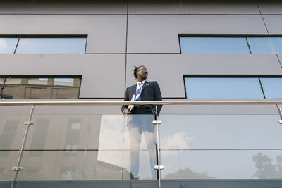 Businessman holding laptop while standing at office building