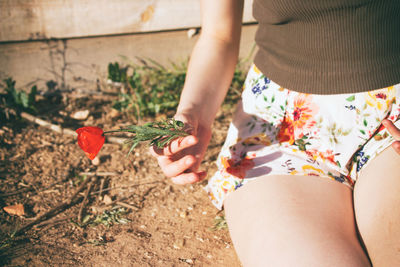 Low section of woman holding flowers