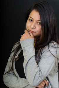 Portrait of young woman against black background