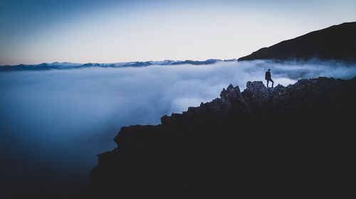 Silhouette person standing on mountain against sky