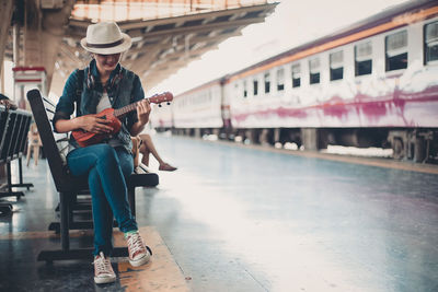 Full length of man sitting on guitar