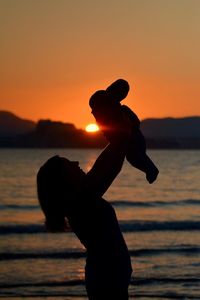 Silhouette of people in sea at sunset