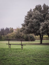 Park bench on field against clear sky