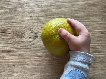 Close-up of hand holding fruit on table