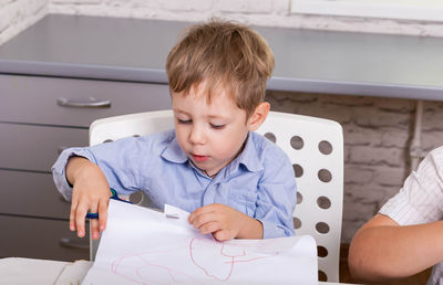 Portrait of cute boy sitting on table