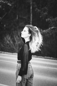 Portrait of young woman standing against wall