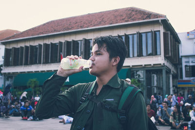 Portrait of young man drinking food in city