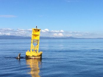 Lighthouse on calm sea against blue sky