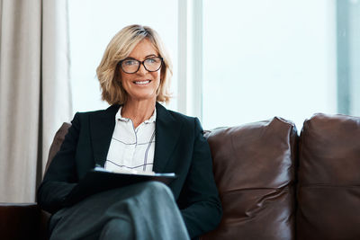 Portrait of young businesswoman using laptop while sitting on sofa at home