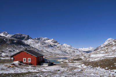 Snow covered houses and mountains against clear blue sky