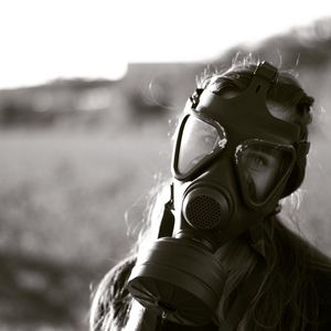 Close-up of young woman wearing gas mask on field