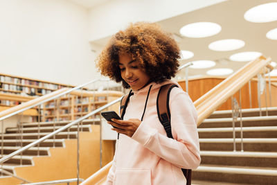 Girl using smart phone in library