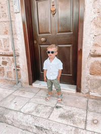 Full length portrait of boy standing against door