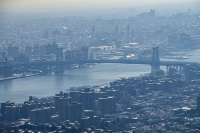 High angle view of illuminated cityscape by sea against sky