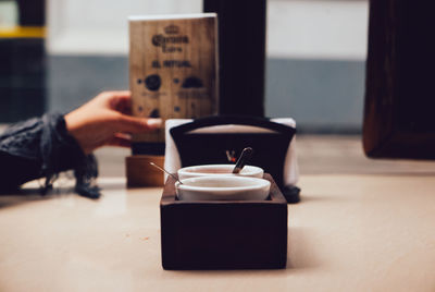 Close-up of hand holding coffee cup on table