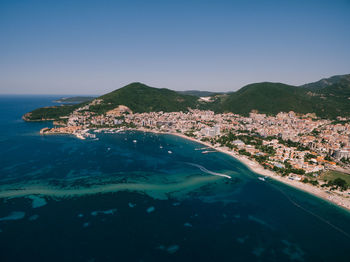 Aerial view of city by sea against clear sky