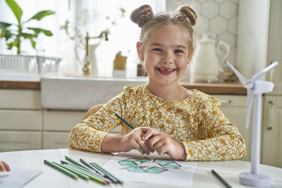 Portrait of a smiling girl sitting on table