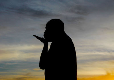 Silhouette of a man against cloudy sky at sunset