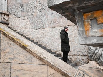 Low angle portrait of man standing on steps against wall