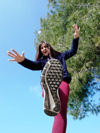 Young woman with arms raised against sky