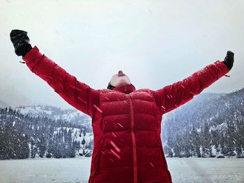 Man with red umbrella standing in snow