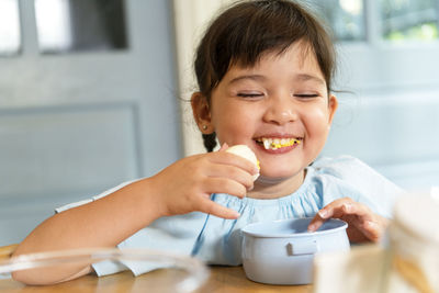 Cute girl eating egg at home