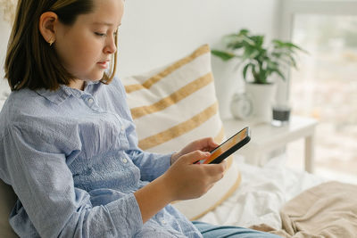 Young woman using mobile phone while sitting at home