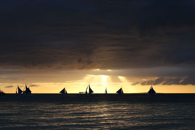 Silhouette sailboats in sea against sky during sunset