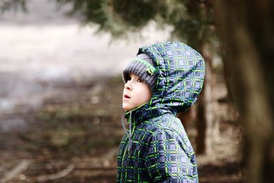 Close-up of boy standing against tree